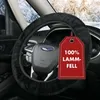 A close-up of a car's steering wheel covered with a black sheepskin cover, with a red tag hanging from it. Produktbild-Vorschau