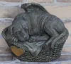 A stone sculpture of a sleeping dog with wings, lying in a basket, placed against a brick wall. Anteprima dell’immagine prodotto