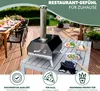 A pizza oven is set up on a table on a wooden deck, with a dining table and chairs in the background. Produktbild-Vorschau
