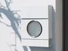 A white mailbox mounted on a white wall with tree shadows. Podgląd zdjęcia produktu