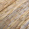A close-up, diagonal view of a reed fence or screen made of many thin, natural-colored reeds bound together with black string. Produktbild-Vorschau