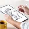 A person is using a stylus to draw on a tablet, with a cup of coffee nearby. Produktbild-Vorschau
