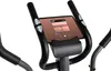 Close-up of the console of an exercise bike, showing the handlebars and a tablet holder with a tablet displaying a music interface. Produktbild-Vorschau