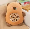 A plush toy is placed on a textured surface, possibly a chair or sofa, with books in the background. Anteprima dell’immagine prodotto
