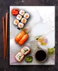 A close-up of a glass cutting board with a sushi arrangement and orchids. Voir les images du produit