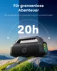 A portable speaker is placed on rocks in a mountainous landscape with a gradient sky. Voir les images du produit