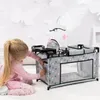 A young girl is playing with a doll's crib, which has a changing station and a mobile. Produktbild-Vorschau