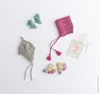 A flat lay of baby knitwear items including hats and booties, along with a milestone card. Produktbild-Vorschau