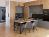 A modern dining room with a wooden table and chairs, set against a kitchen backdrop. Produktbild-Vorschau