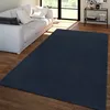 A dark blue rug is placed on a wooden floor in front of a white sofa in a living room.