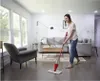 A woman is cleaning the floor in a living room with a spray mop. Anteprima dell’immagine prodotto