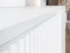 A close-up, angled view of a white cabinet with vertical fluting. Náhľad obrázku produktu