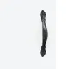 A black cabinet handle with ornate detailing is shown against a white background. Voir les images du produit