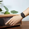 A person's arm with a watch is shown interacting with a wooden stereo system. Produktbild-Vorschau
