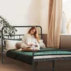 A young woman is reading a book while sitting on a bed. Náhled obrázku produktu