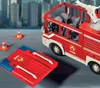 A toy fire truck and accessories are displayed on a surface with a blurred city background. Produktbild-Vorschau