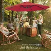 A group of people enjoying a gathering outdoors under a large red cantilever umbrella. Produktbild-Vorschau