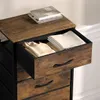 A close-up view of a chest of drawers with one drawer open, revealing folded clothes. Produktbild-Vorschau