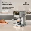 A silver espresso machine on a kitchen counter, with bread slices on a wooden board in the foreground. Produktbild-Vorschau