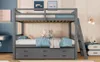 A grey wooden bunk bed with a pull-out trundle bed, set up in a child's bedroom with decorative items. Voir les images du produit