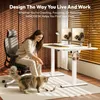 A woman is playing with her cat next to a standing desk in a home office. Produktbild-Vorschau
