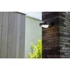 An outdoor wall light mounted on a brick pillar next to a wooden fence. Produktbild-Vorschau