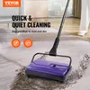 A person is using a manual carpet sweeper on a rug in a room. Náhled obrázku produktu