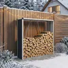 A firewood storage shed filled with logs, set against a wooden fence in a snowy outdoor environment with a house in the background. Podgląd zdjęcia produktu