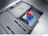 Close-up of a dishwasher detergent dispenser with a detergent pod and a red rinse aid indicator. Náhled obrázku produktu