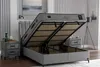 A bed with its storage compartment open, revealing the mattress and internal mechanisms. It is shown in a bedroom setting with nightstands and artwork. Produktbild-Vorschau