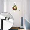 A Christmas wreath is hanging on a white door in a hallway, with a close-up inset showing the detail of a door hook. Produktbild-Vorschau