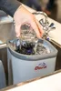 A person is washing a glass in a sink using a glass washing device. Podgląd zdjęcia produktu