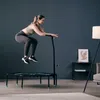 A woman is jumping on a trampoline in a room. Voir les images du produit
