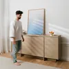 A man walks past a wooden sideboard with a mirror and fruit bowl on top. Produktbild-Vorschau