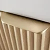 A close-up view of a cabinet with a gold handle and ribbed wooden front. Náhled obrázku produktu