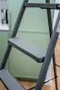 Close-up of a gray stepladder with green cabinets in the background. Anteprima dell’immagine prodotto