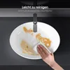 A hand is cleaning a white ceramic sink with a cloth, demonstrating its easy-to-clean surface. Produktbild-Vorschau