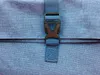 A close-up view of a blue fabric backpack with a black buckle and strap. Produktbild-Vorschau