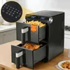 A black dual-chamber air fryer is shown on a wooden table, with one drawer filled with french fries and the other with a roasted chicken. The top of the air fryer displays the temperature. Anteprima dell’immagine prodotto