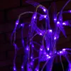 A close-up of a decorative tree with purple LED lights and leaf-shaped accents, set against a brick wall. Podgląd zdjęcia produktu
