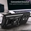A black phone case with a ring stand is shown on a wooden surface, with a laptop and headphones in the background. Produktbild-Vorschau