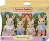 The image shows the retail packaging of a Sylvanian Families Milk Rabbit Family toy set. The packaging features a scene with the rabbit figures in front of a house and garden. Podgląd zdjęcia produktu
