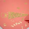 A close-up of a pink surface with gold foil decorations, including a school cone and numbers. Produktbild-Vorschau