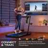 A woman is running on a treadmill in a modern living room, with a large TV screen displaying a running simulation. Produktbild-Vorschau
