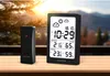 A Sencor weather station and its outdoor sensor are placed on a wooden table in front of a window with a blurred outdoor view. Náhled obrázku produktu
