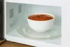 A white bowl of tomato soup sits on a glass turntable inside a microwave. Náhled obrázku produktu