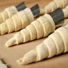 Several pastry cones are being prepared on a wooden surface. Podgląd zdjęcia produktu