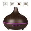 A dark wood-grain aroma diffuser with a purple LED light ring and control buttons at the base. Four icons are displayed above the diffuser, indicating features. Produktbild-Vorschau