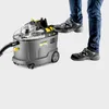 A person is stepping on a Kärcher Puzzi 9/1 BP Waschsauger. Produktbild-Vorschau