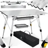 A foldable camping table with its accessories, including a carrying bag and storage baskets, displayed against a white background. Produktbild-Vorschau
